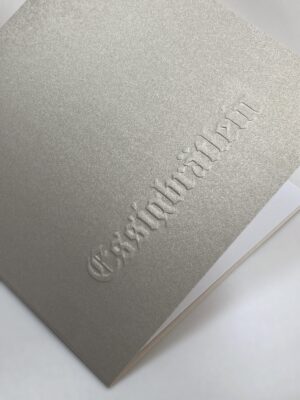 Umschlag des Essigbrätlein-Gutscheins: eine Blindprägung auf feingeriffeltem, champagnerfarben schimmerndem Gmund-Feinstpapier.
